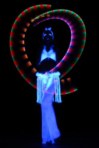 Tänzerin bei einer Blacklight LED Show in weissem Kostüm umgeben von bunten Lichtkreisen