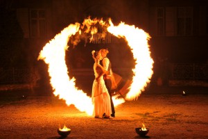 Feuerartistenpaar bei Feuershow für Hochzeit umgeben von Flammenschweif